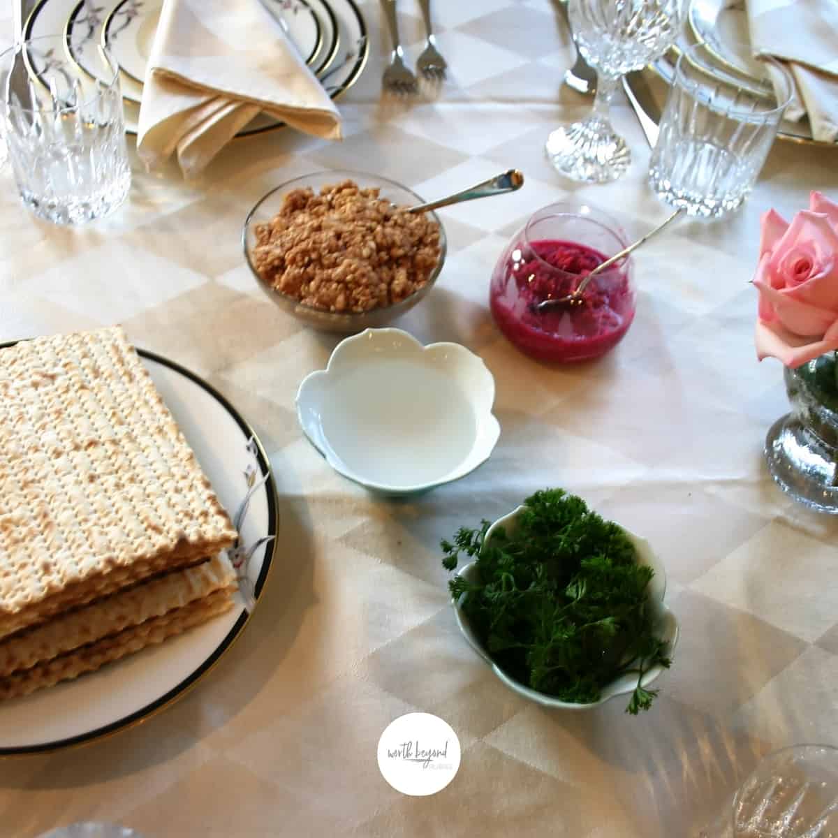a table set for a Passover seder and the Worth Beyond Rubies logo at the bottom of the image