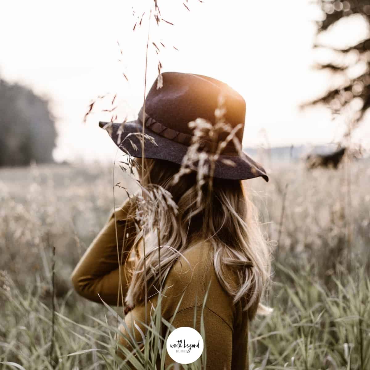 A woman in a hat in a field looking away for post called 3 Strategies for How to Overcome Fear Biblically