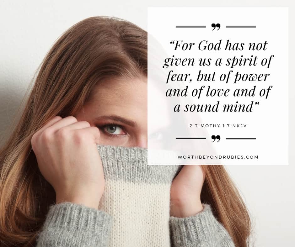 A woman with her face partially tucked into her sweater and 2 Timothy 1:7 quoted in NKJV for post on overcoming the spirit of fear