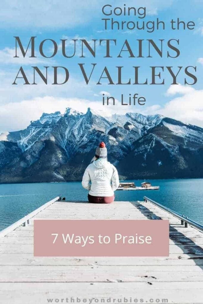 A WOMAN SITTING ON A DOCK IN FRONT OF A MOUNTAIN AND TEXT THAT SAYS MOUNTAINS AND VALLEYS IN LIFE - 7 WAYS TO PRAISE