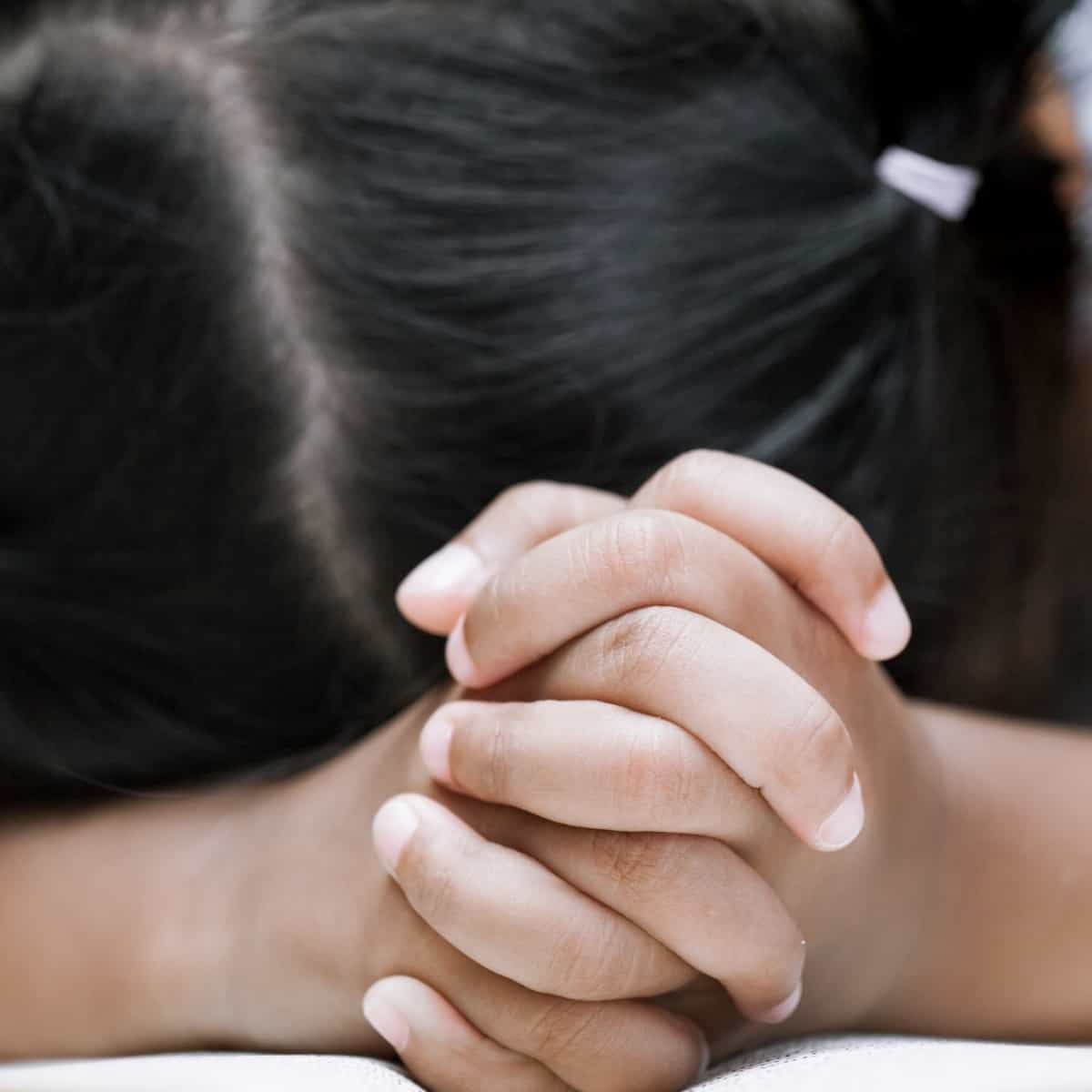 a girl with her head on a table and her hands folded in front of her for post titled Teach Me How to Pray - Power in Praying the Lord's Prayer