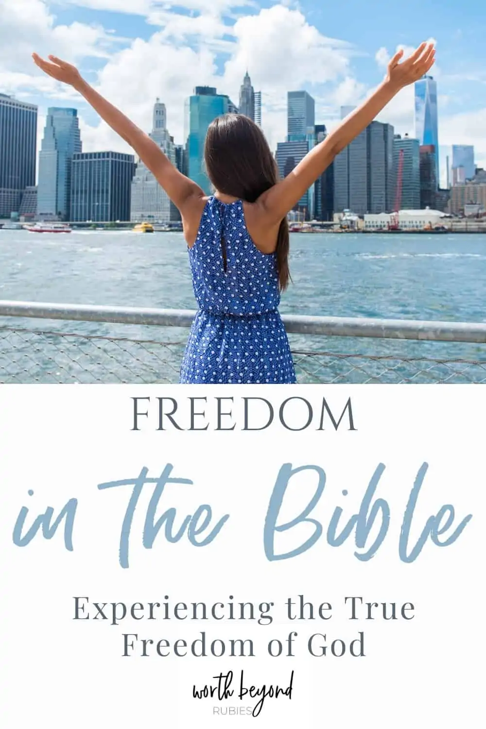 An image of a woman standing on the river facing the New York City skyline and she is wearing a blue, polka dot dress and her arms are up in the air toward the sky - a text overlay that says Freedom in the Bible - Experiencing the True Freedom of God