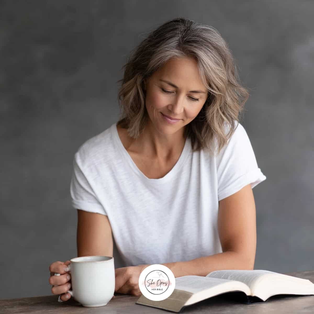 a woman reading a book and holding a coffee cup
