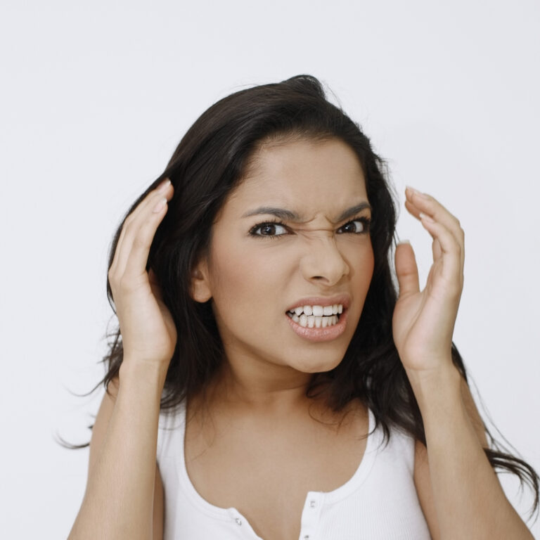 An image of a Latina woman with her hands up to her head looking like she is very frustrated