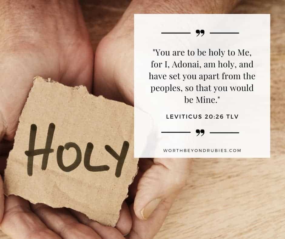 A persons's hands cupped holding a piece of cardboard with the word "Holy" written on it in marker and Leviticus 20:26 quoted in the tree of life version in the upper corner of the image - Be Holy For I am Holy