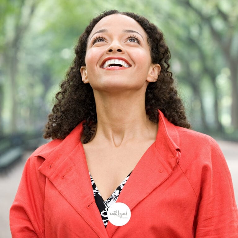 An image a beautiful black woman with long hair, wearing a reddish/orange jacket, standing on a walkway that is covered in trees and she is looking up in amazement at them for post entitled The Promises of God - God Will Make This Trial a Blessing