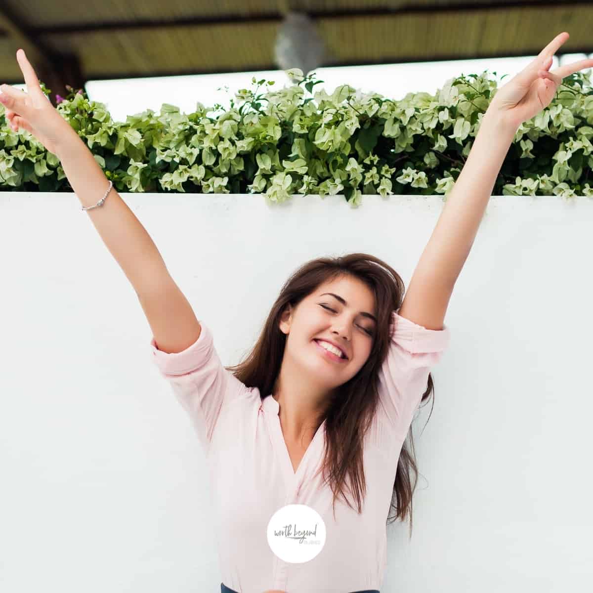 Happy woman with arms in air for post called What is Freedom in Christ- Breaking Bonds of Sin!