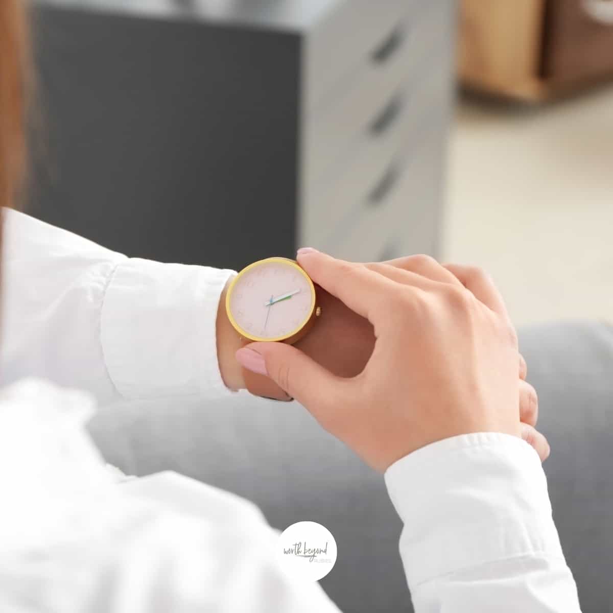 a woman's hand holding her watch on her wrist like she is looking at the time and the Worth Beyond Rubies logo at the bottom of the image