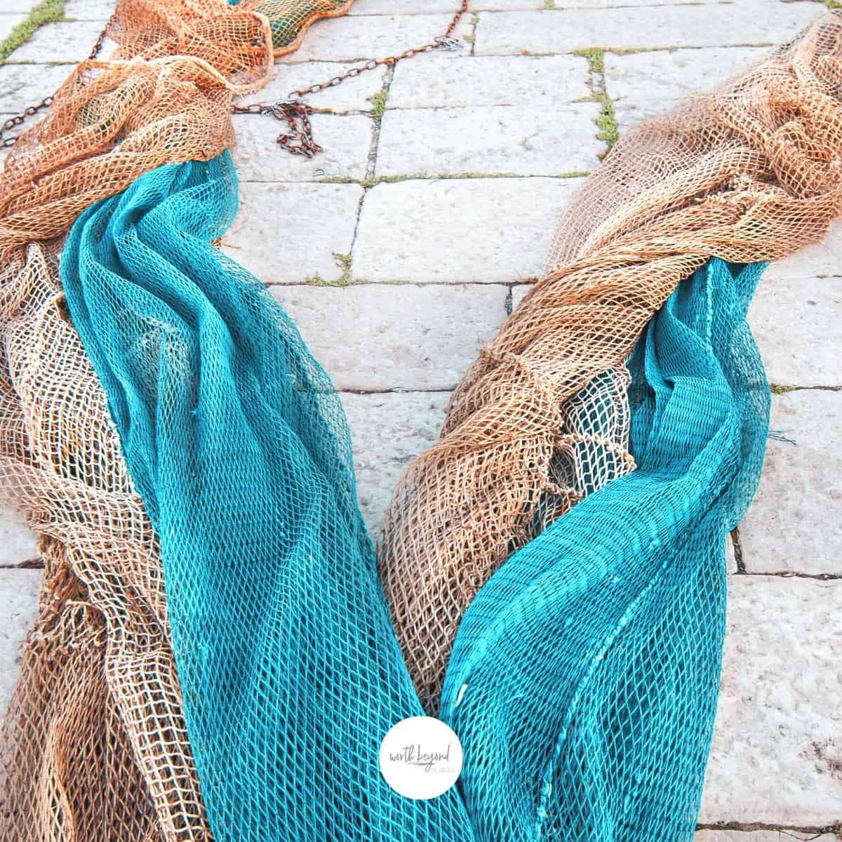 colored fishing nets on the ground and the Worth Beyond Rubies logo at the bottom of the image