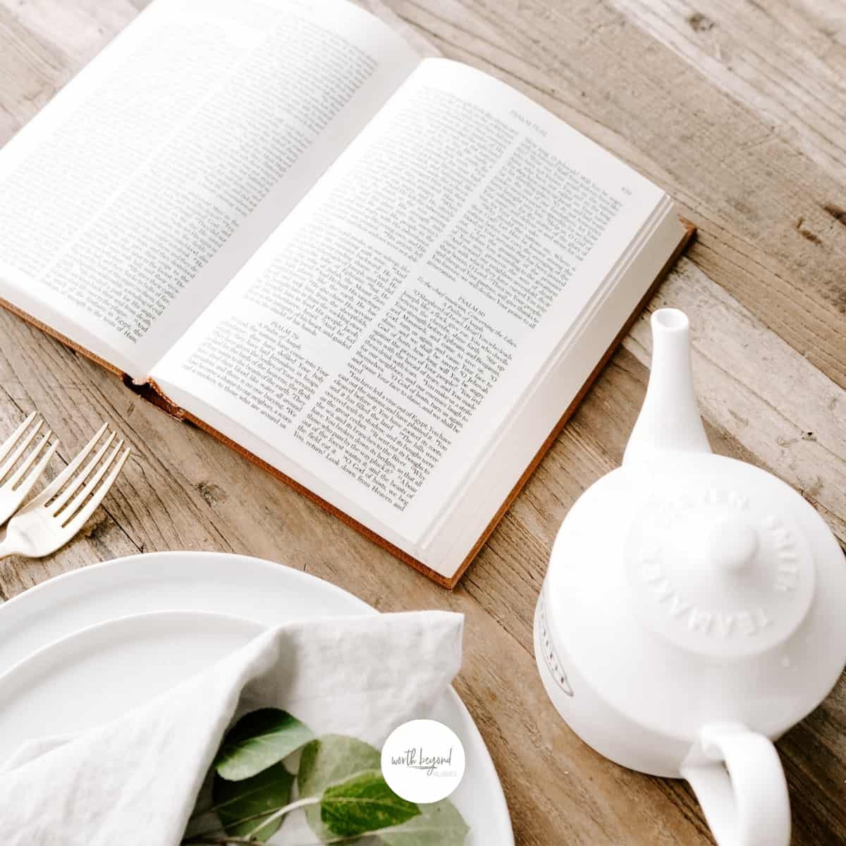 an image of a bible on a table next to a tea pot and a plate with forks and the Worth Beyond Rubies logo at the bottom