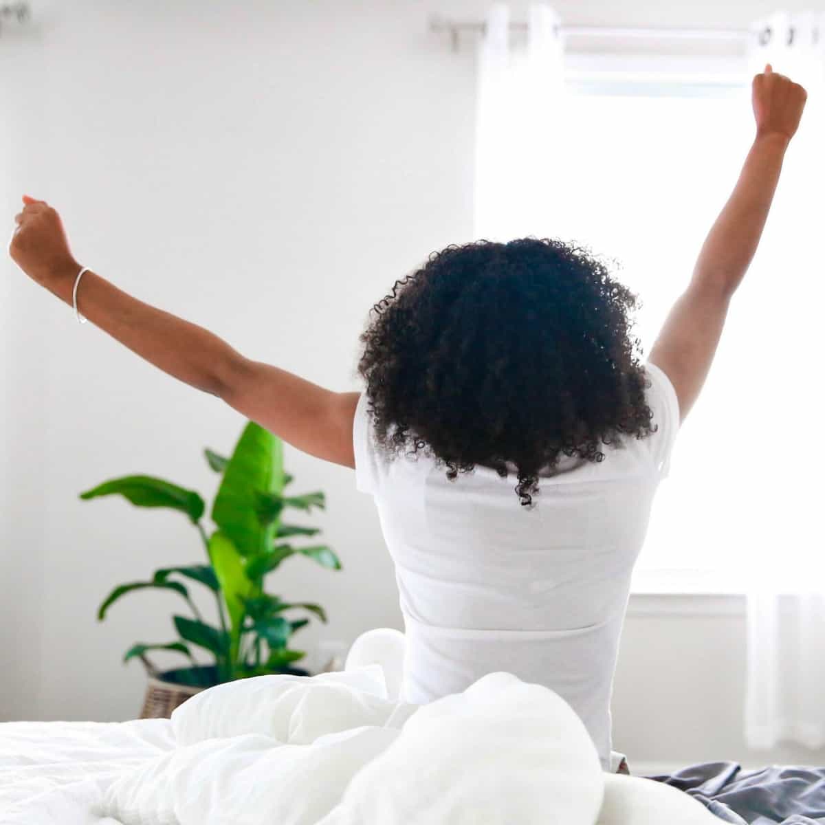 a woman facing a window sitting on a bed stretching up for post called Prayer Changes Things