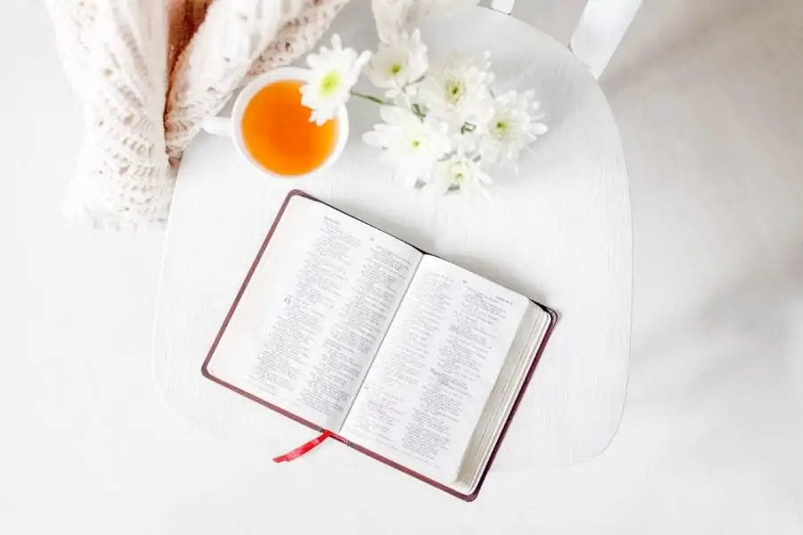 A bible open next to a cup of tea and some flowers