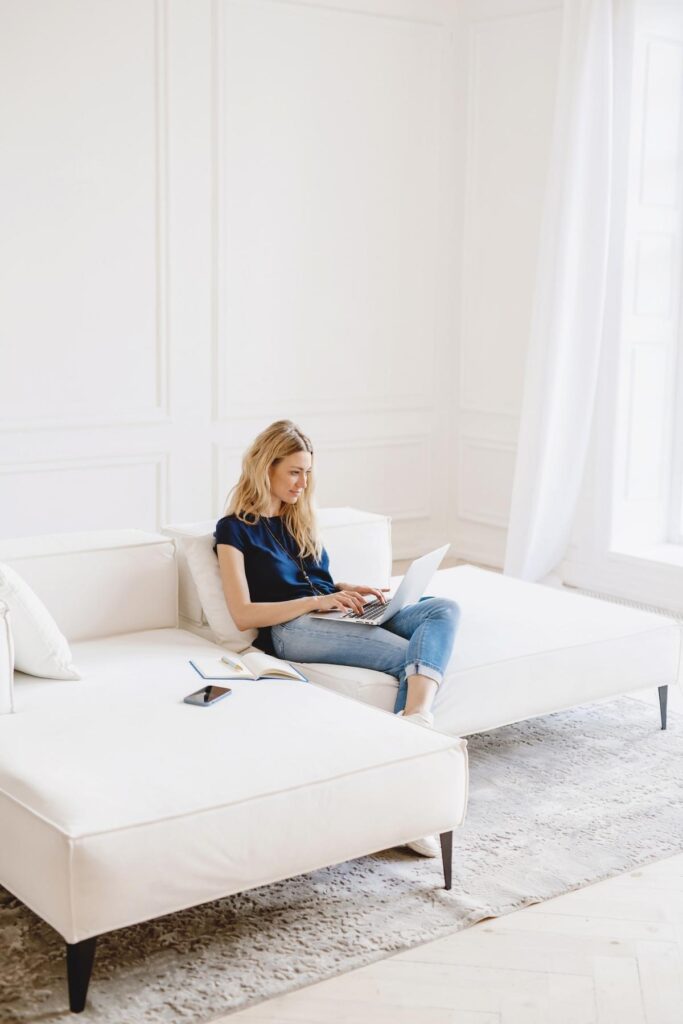 a woman on a white couch on a laptop