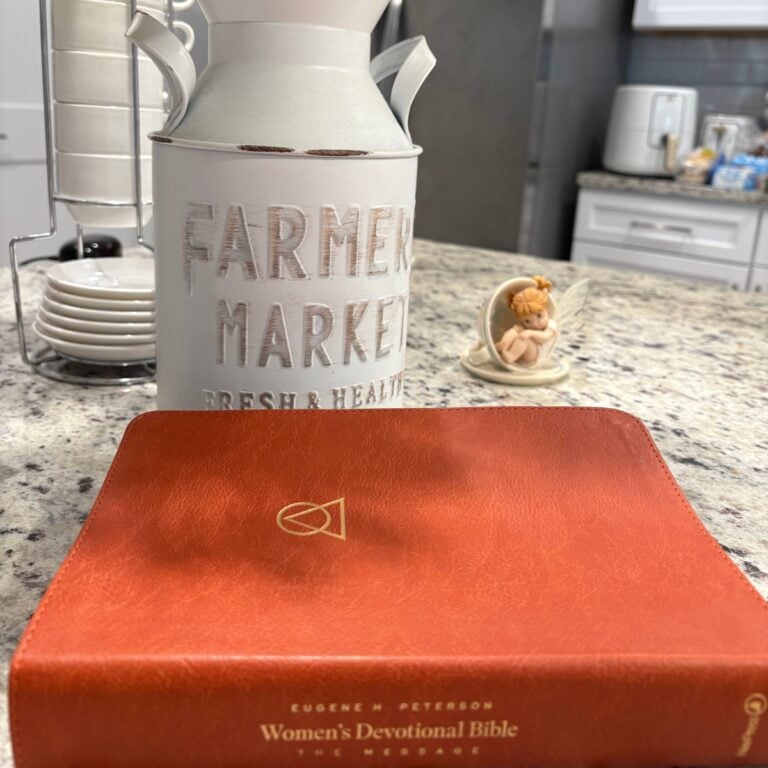 a white metal pitcher next to a red book